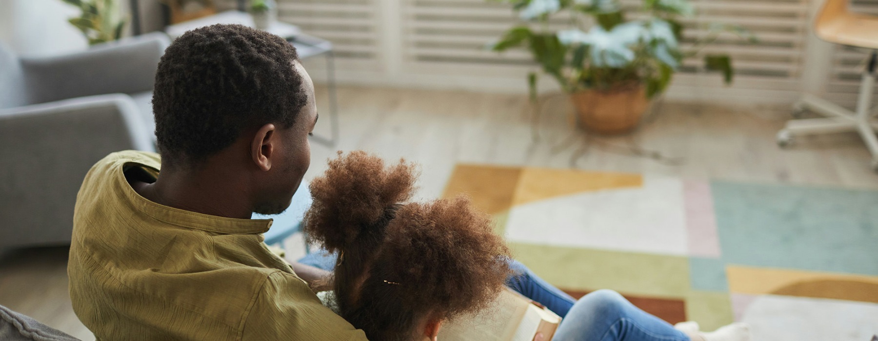 a man and child reading a book in a living room